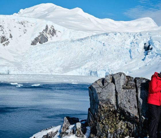 A couple of guests happily poses near grey rocks in Antarctica.