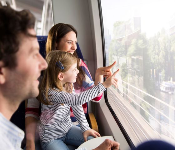 Parents and child looking outside window of the train