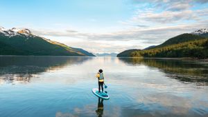 Woman paddleboarding on a glassy water lake on Alaska