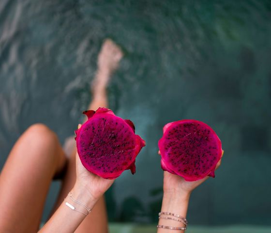Person holding two pink fruits in canggu indonesia